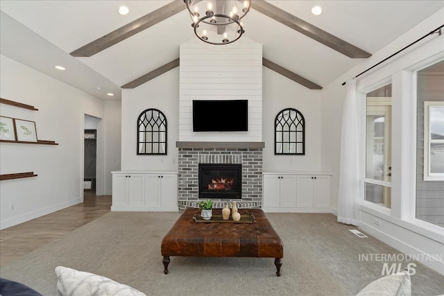 carpeted living area with a large fireplace, baseboards, visible vents, and beam ceiling