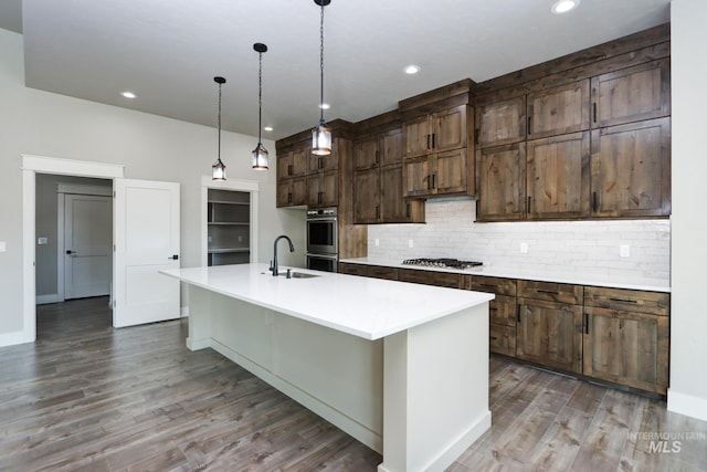 275 Meadow View Dr, Payette, ID 83661 - kitchen with stainless steel appliances, decorative backsplash, wood finished floors, light countertops, and a kitchen island with sink