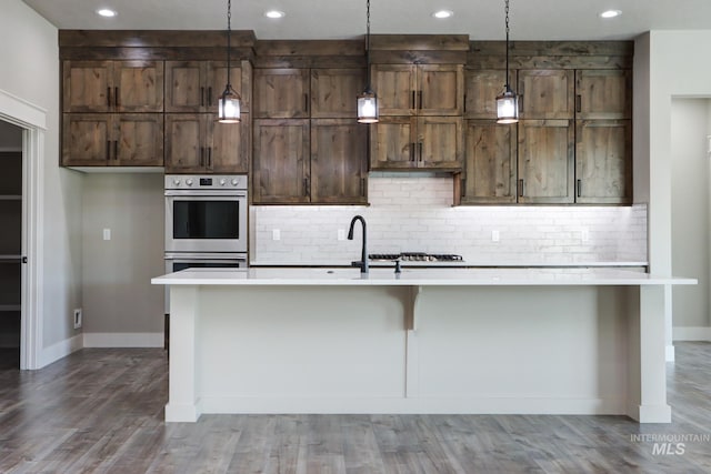 275 Meadow View Dr, Payette, ID 83661 - kitchen with light countertops, tasteful backsplash, a kitchen island with sink, wood finished floors, and stainless steel double oven