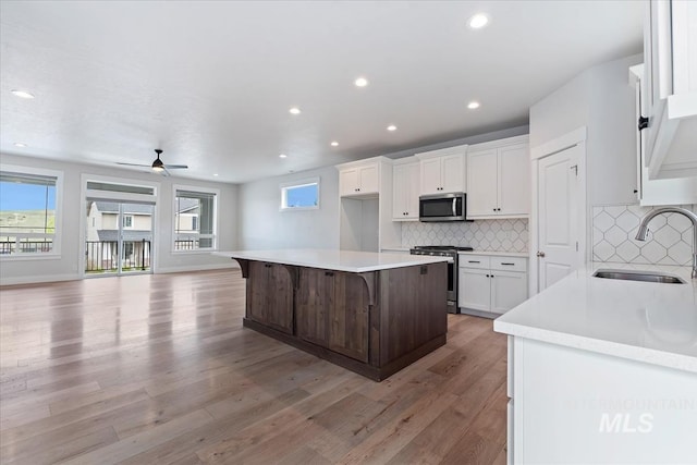 19322 N Shepherds Pie Pl, Boise, ID 83714 - kitchen featuring appliances with stainless steel finishes, a sink, open floor plan, white cabinetry, and a center island