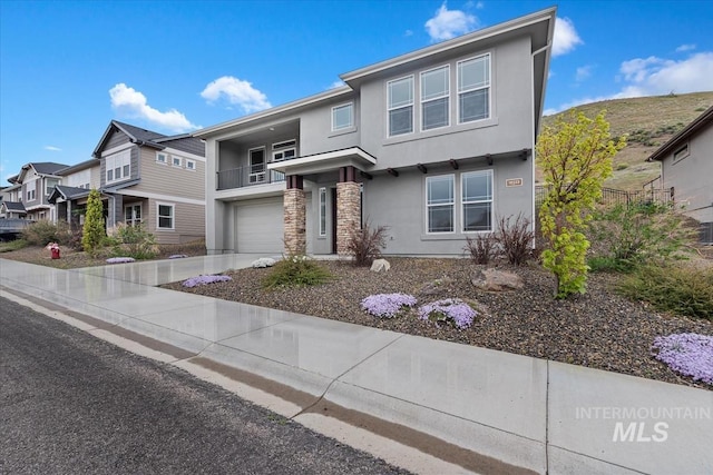 19322 N Shepherds Pie Pl, Boise, ID 83714 - view of front facade featuring stucco siding, a garage, a balcony, driveway, and stone siding
