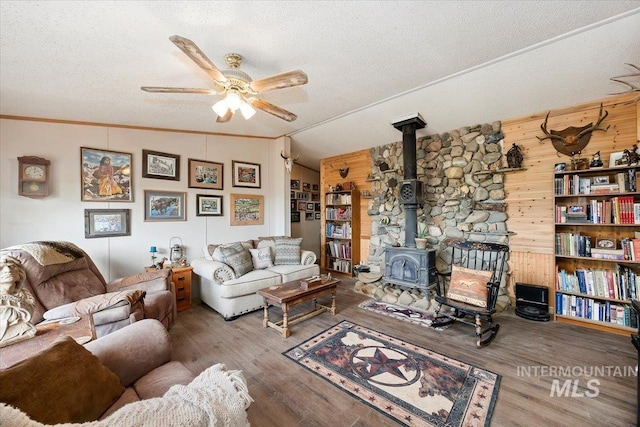 103 W 420 N, Shoshone, ID 83352 - living area featuring a wood stove, a textured ceiling, wooden walls, ceiling fan, and wood finished floors