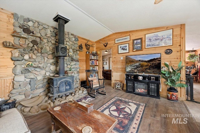 103 W 420 N, Shoshone, ID 83352 - living room featuring wood walls, lofted ceiling, a wood stove, wood finished floors, and a warm lit fireplace