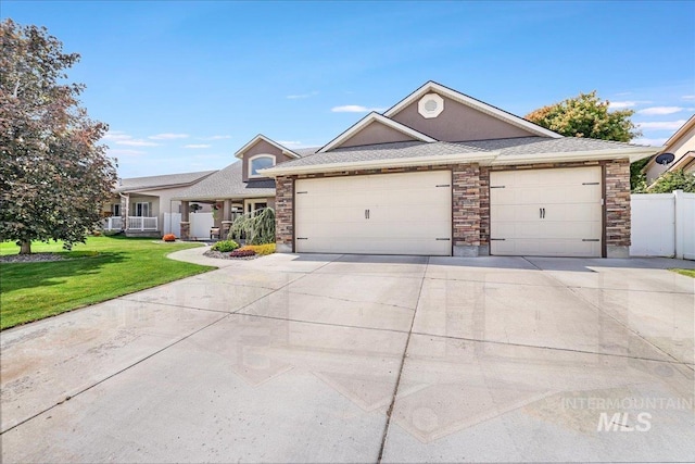 1021 Ballard Ln, Kimberly, ID 83341 - view of front of house featuring a garage, concrete driveway, a shingled roof, and stone siding