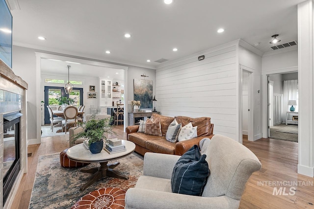 living room featuring hardwood / wood-style flooring, ornamental molding, and wood walls