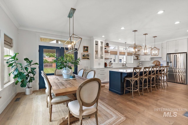 dining room featuring light hardwood / wood-style flooring, crown molding, and sink