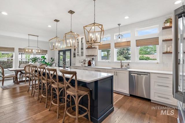 kitchen with pendant lighting, a center island, white cabinets, sink, and stainless steel dishwasher