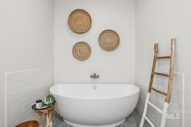 bathroom featuring a washtub, tile walls, and tile patterned flooring