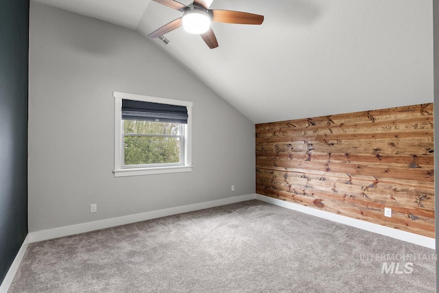 spare room with wooden walls, carpet, lofted ceiling, and ceiling fan