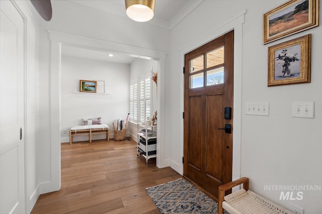 entryway featuring crown molding and light hardwood / wood-style flooring