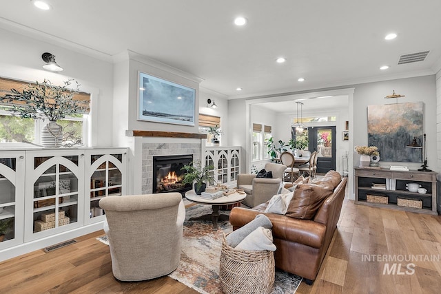 living room with crown molding, a fireplace, and light hardwood / wood-style floors