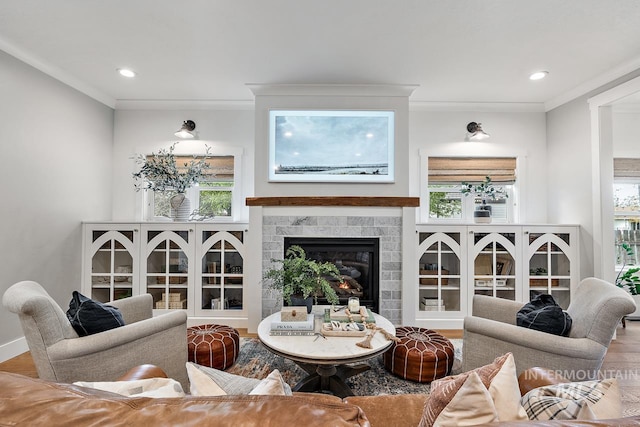 living room featuring a tile fireplace, hardwood / wood-style flooring, and crown molding