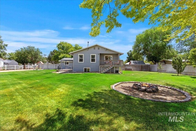 rear view of house with a wooden deck, an outdoor fire pit, and a lawn