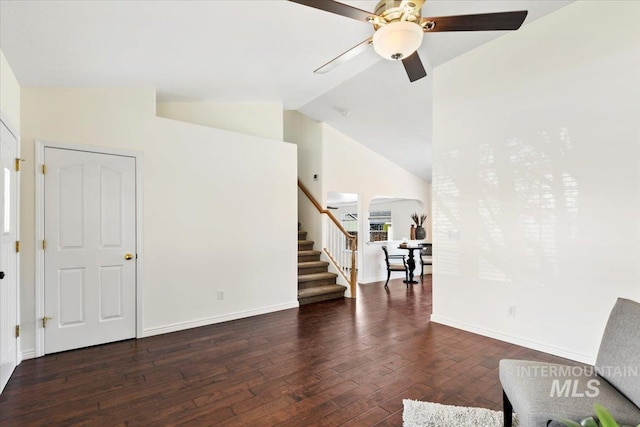 living area with stairs, high vaulted ceiling, hardwood / wood-style flooring, a ceiling fan, and baseboards