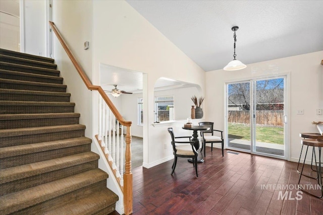stairway with baseboards, high vaulted ceiling, wood finished floors, and a ceiling fan