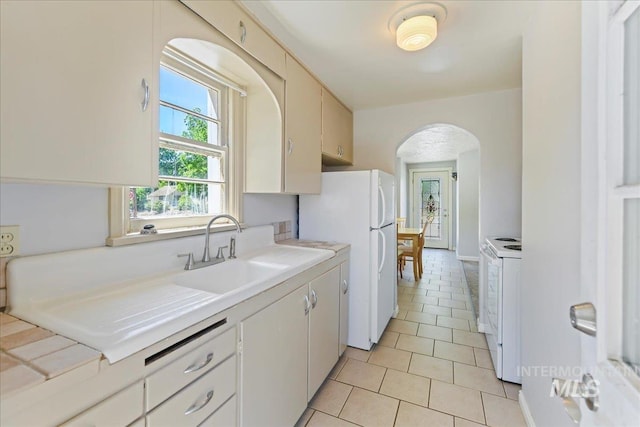 404 W 5th St, Weiser, ID 83672 - kitchen with arched walkways, white appliances, a sink, light tile patterned flooring, and light countertops