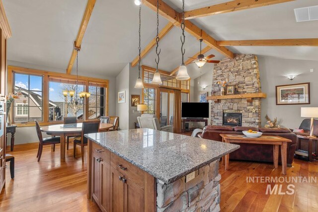 1391 Greystone Dr, Mccall, ID 83638 - kitchen featuring a stone fireplace, light wood-style flooring, a kitchen island, a chandelier, and light stone countertops