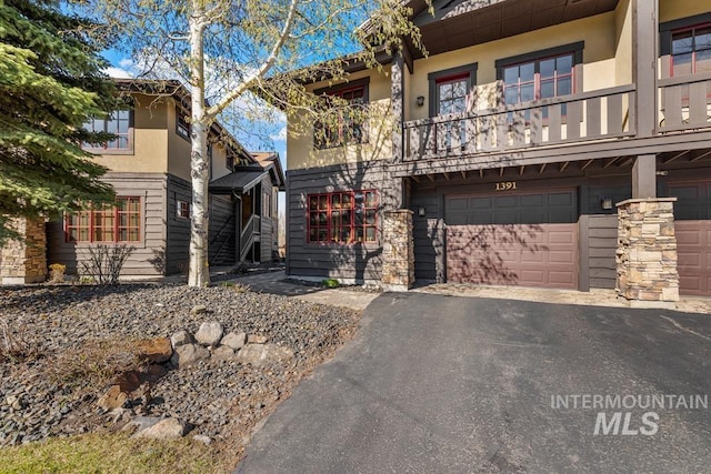 1391 Greystone Dr, Mccall, ID 83638 - view of front facade featuring an attached garage, stucco siding, asphalt driveway, and a balcony