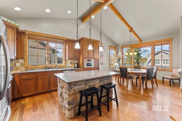 1391 Greystone Dr, Mccall, ID 83638 - kitchen featuring appliances with stainless steel finishes, brown cabinets, light wood-style floors, light stone countertops, and healthy amount of natural light