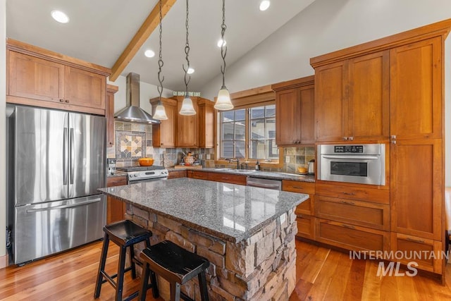 1391 Greystone Dr, Mccall, ID 83638 - kitchen with appliances with stainless steel finishes, wall chimney range hood, brown cabinetry, tasteful backsplash, and high vaulted ceiling