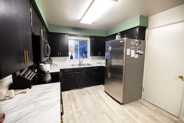 611 E Hawaii Ave, Nampa, ID 83686 - kitchen with stainless steel appliances, dark cabinetry, light wood-type flooring, and decorative backsplash
