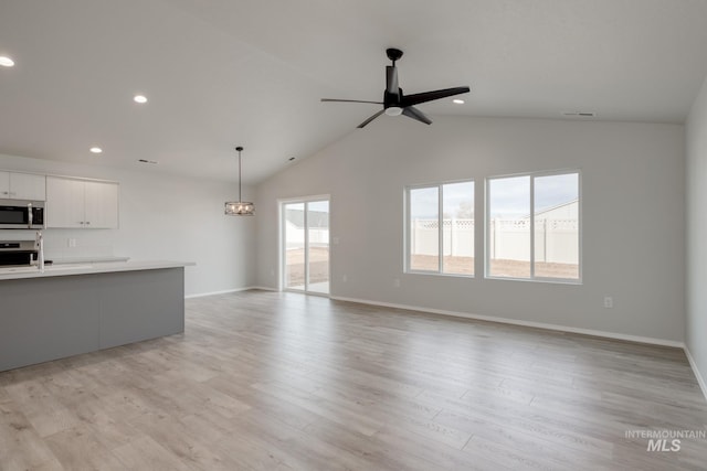 unfurnished living room with light wood-style floors, recessed lighting, vaulted ceiling, and ceiling fan with notable chandelier