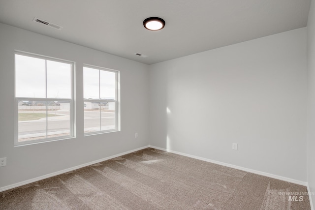 empty room with carpet floors, visible vents, and baseboards