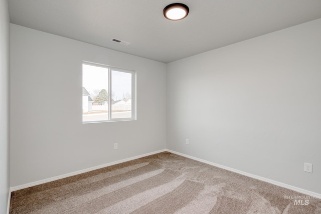 empty room with carpet, visible vents, and baseboards