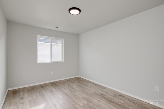 unfurnished room with baseboards, visible vents, and light wood-style floors