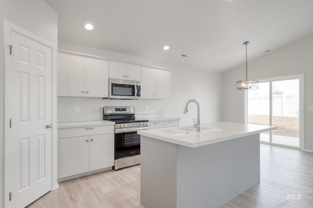 kitchen with a sink, stainless steel appliances, light countertops, and a kitchen island with sink