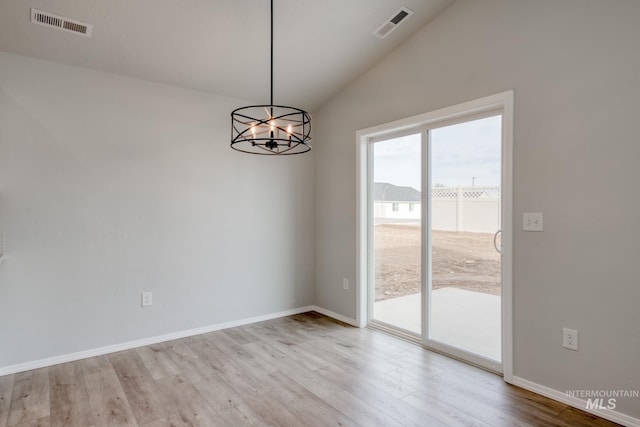 spare room with light wood-style floors, visible vents, and an inviting chandelier