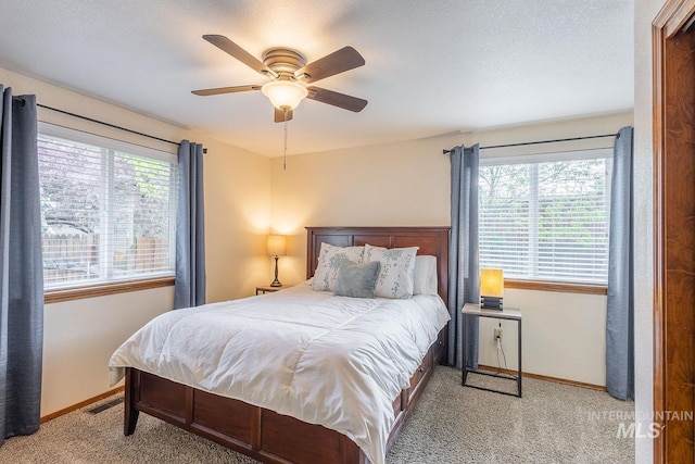 carpeted bedroom featuring a ceiling fan, baseboards, and multiple windows