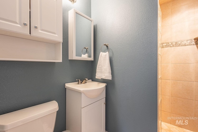 bathroom with vanity, a textured wall, and toilet