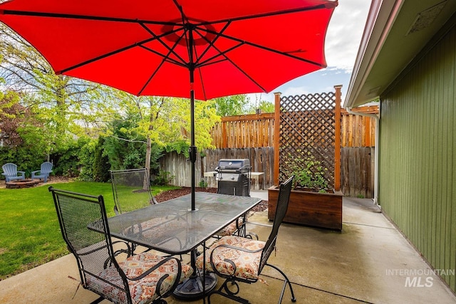 view of patio with area for grilling, a fire pit, outdoor dining area, and a fenced backyard