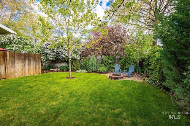 view of yard featuring an outdoor fire pit and fence