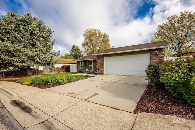 single story home featuring fence, driveway, stone siding, and a garage