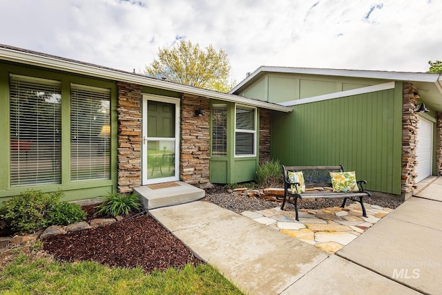 property entrance with a garage and stone siding