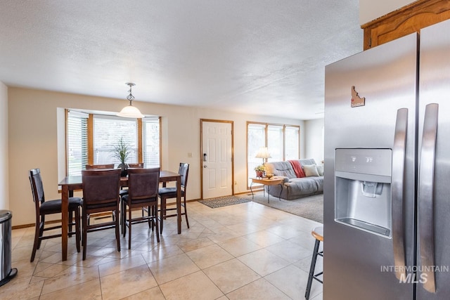 dining area featuring baseboards, a textured ceiling, and a healthy amount of sunlight