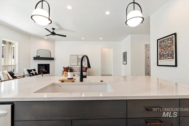 2391 E Snocreek Dr, Eagle, ID 83616 - kitchen featuring a ceiling fan, a fireplace, a sink, light stone counters, and open floor plan
