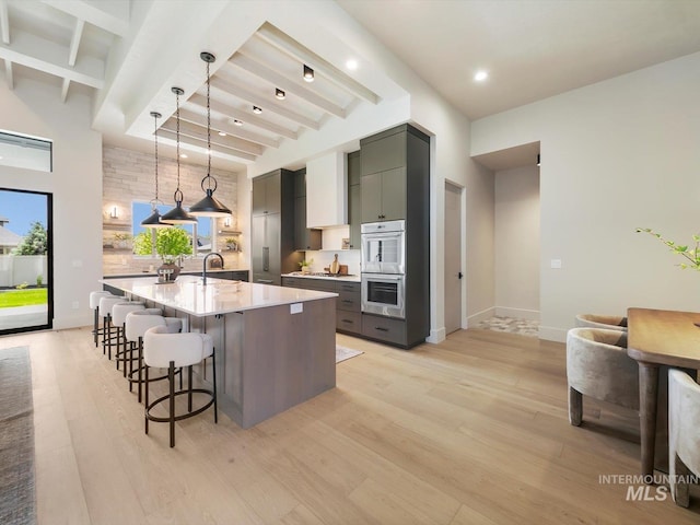 6241 W Strant St, Eagle, ID 83616 - kitchen with beamed ceiling, a sink, light wood-type flooring, light countertops, and a kitchen bar