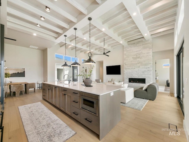 6241 W Strant St, Eagle, ID 83616 - kitchen with stainless steel microwave, beam ceiling, light countertops, a center island with sink, and pendant lighting