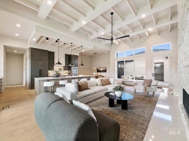 6241 W Strant St, Eagle, ID 83616 - living area with beam ceiling, light wood-style floors, a towering ceiling, a stone fireplace, and recessed lighting