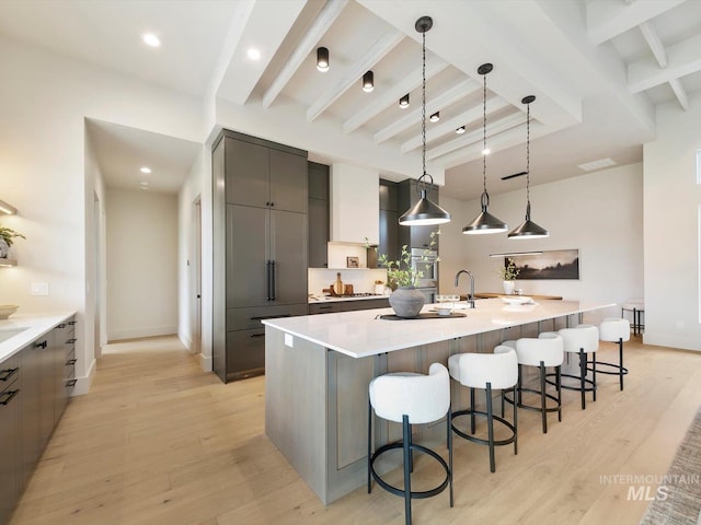 6241 W Strant St, Eagle, ID 83616 - kitchen with beam ceiling, modern cabinets, a spacious island, a breakfast bar, and light wood-style flooring