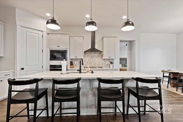 kitchen with white cabinetry, wall chimney exhaust hood, pendant lighting, and a large island