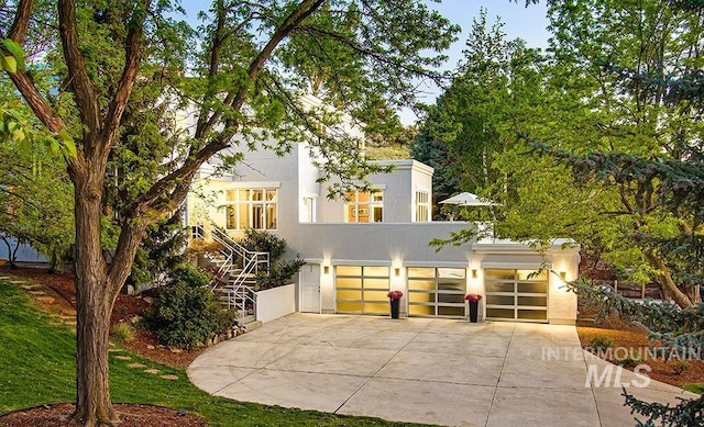 view of front of property with concrete driveway, stucco siding, an attached garage, and stairway