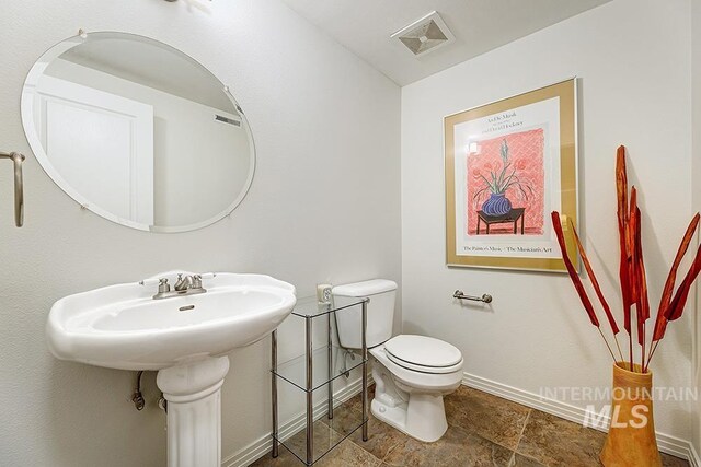 half bathroom with baseboards and toilet