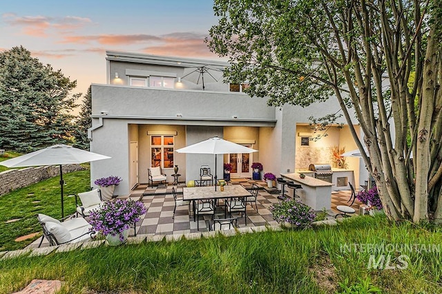 rear view of house featuring exterior kitchen, a patio area, and stucco siding
