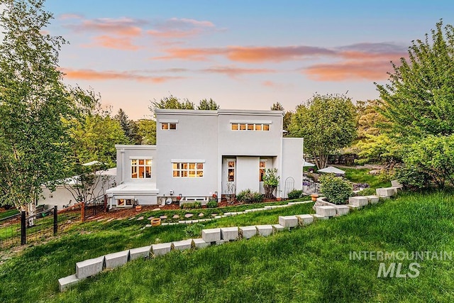 back of property at dusk featuring stucco siding