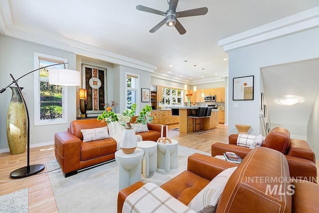 living room featuring healthy amount of natural light, light wood-style flooring, baseboards, ceiling fan, and recessed lighting