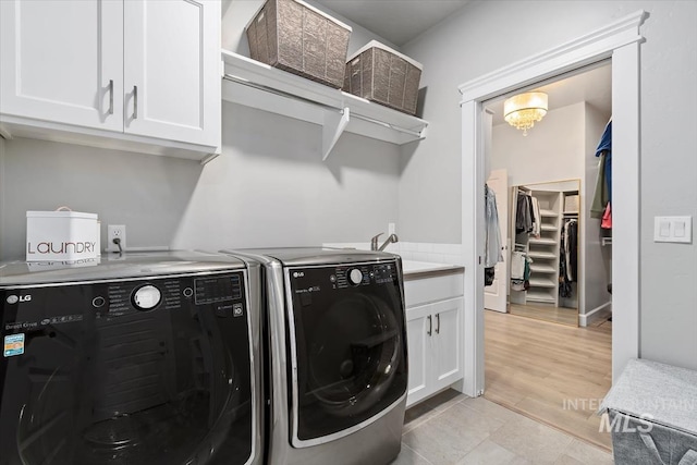 clothes washing area with cabinet space, washing machine and dryer, and an inviting chandelier